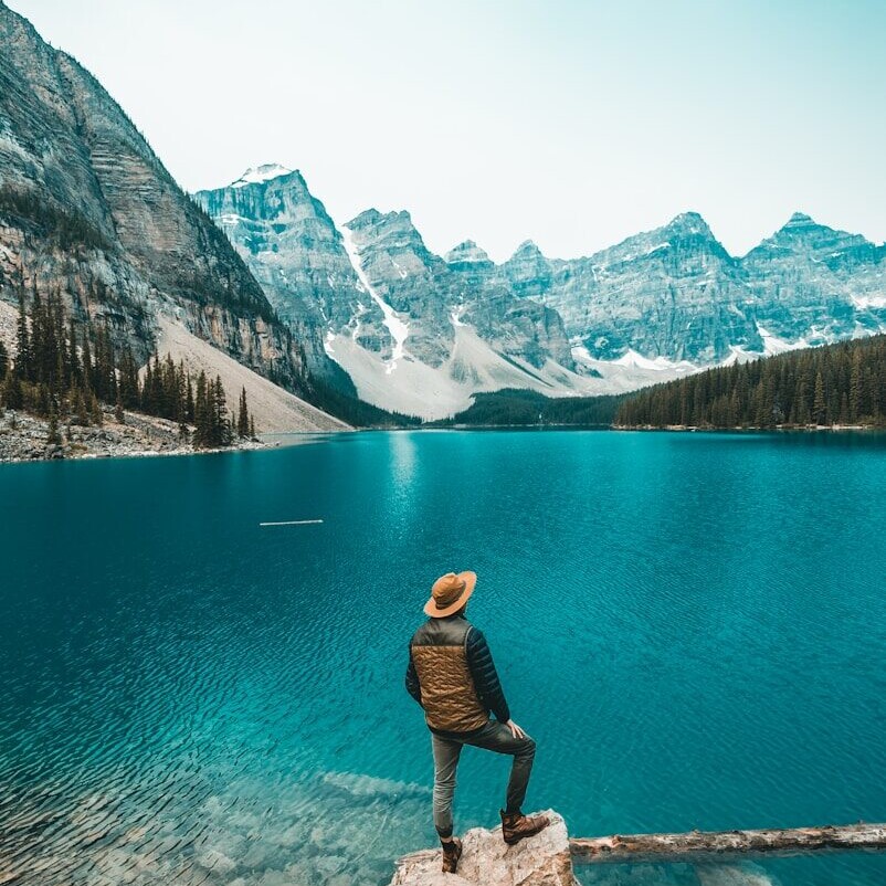 man standing on rock near lake